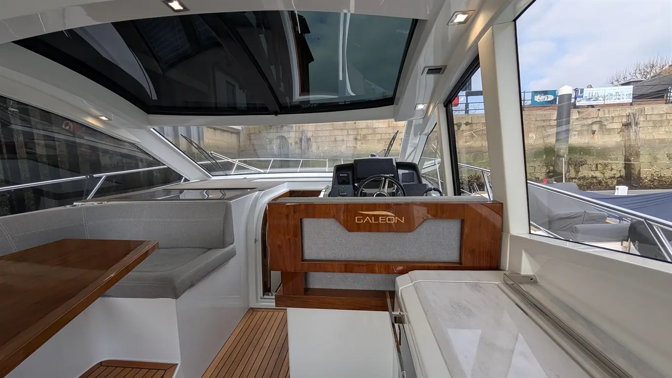 Interior of a Galleon yacht showing a helm, seating area, and stylish design with panoramic windows.